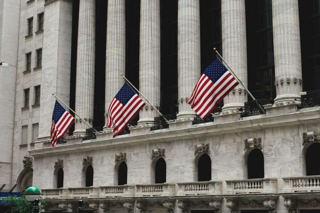 Bygningen til New York Stock Exchange med amerikanske flagg – SEC foreslår å avskaffe obligatorisk kvartalsrapportering