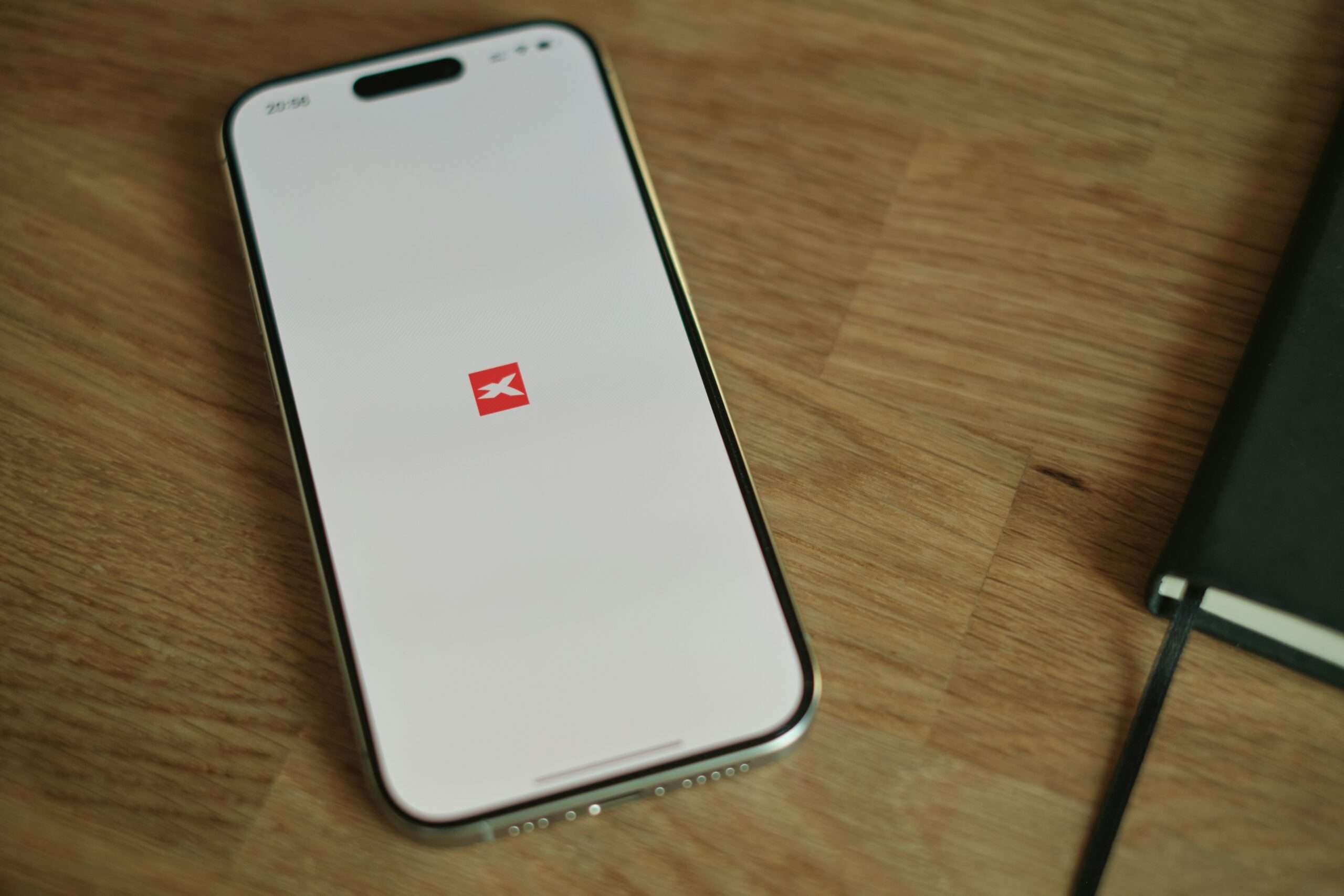 En mobiltelefon med XTB-meglerappen åpen på et trebord