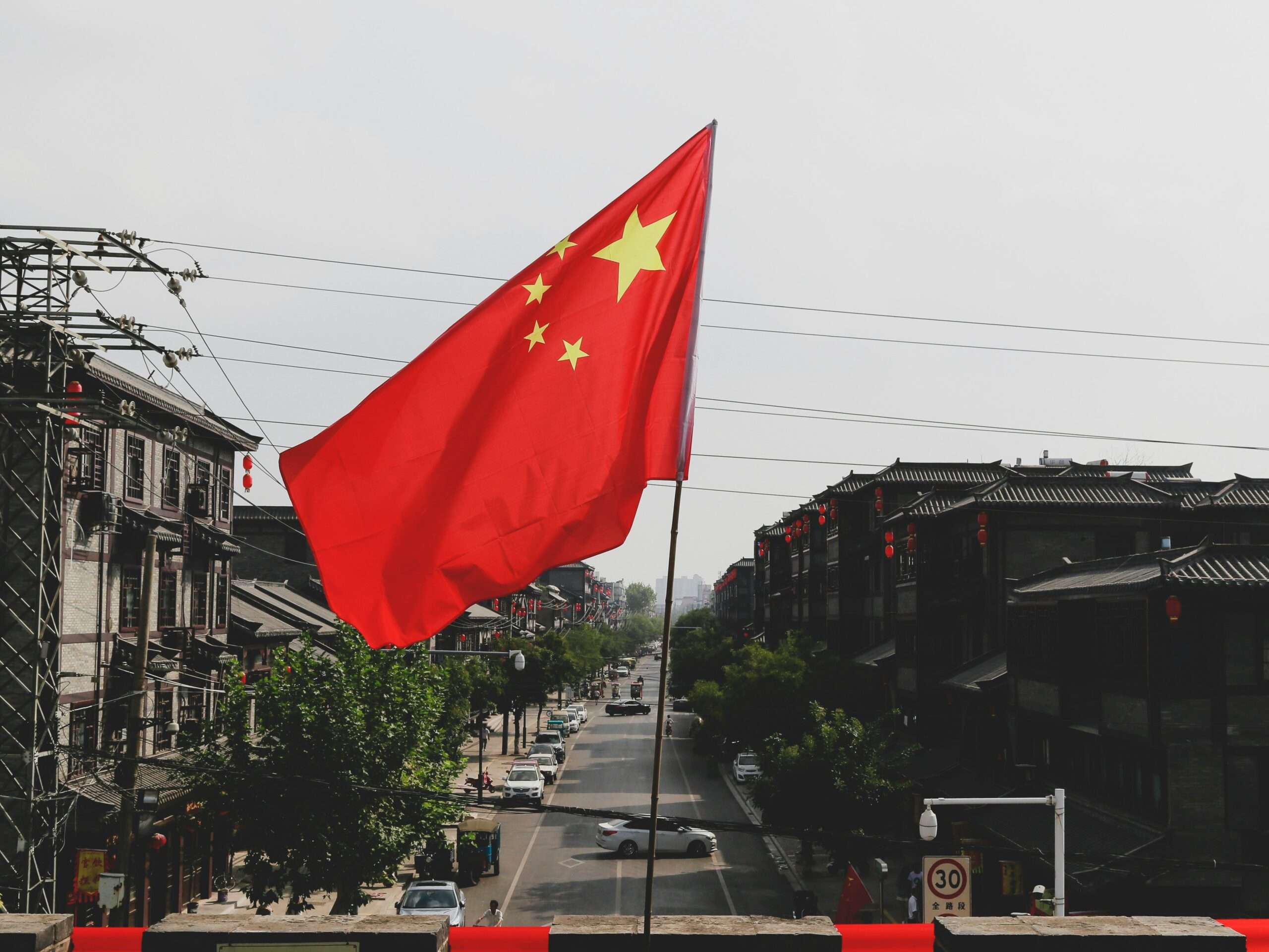 Det kinesiske flagget som vaier over gaten symboliserer Kinas voksende økonomiske makt og forskyvningen av den globale maktbalansen etter toppmøtet mellom Trump og Xi Jinping