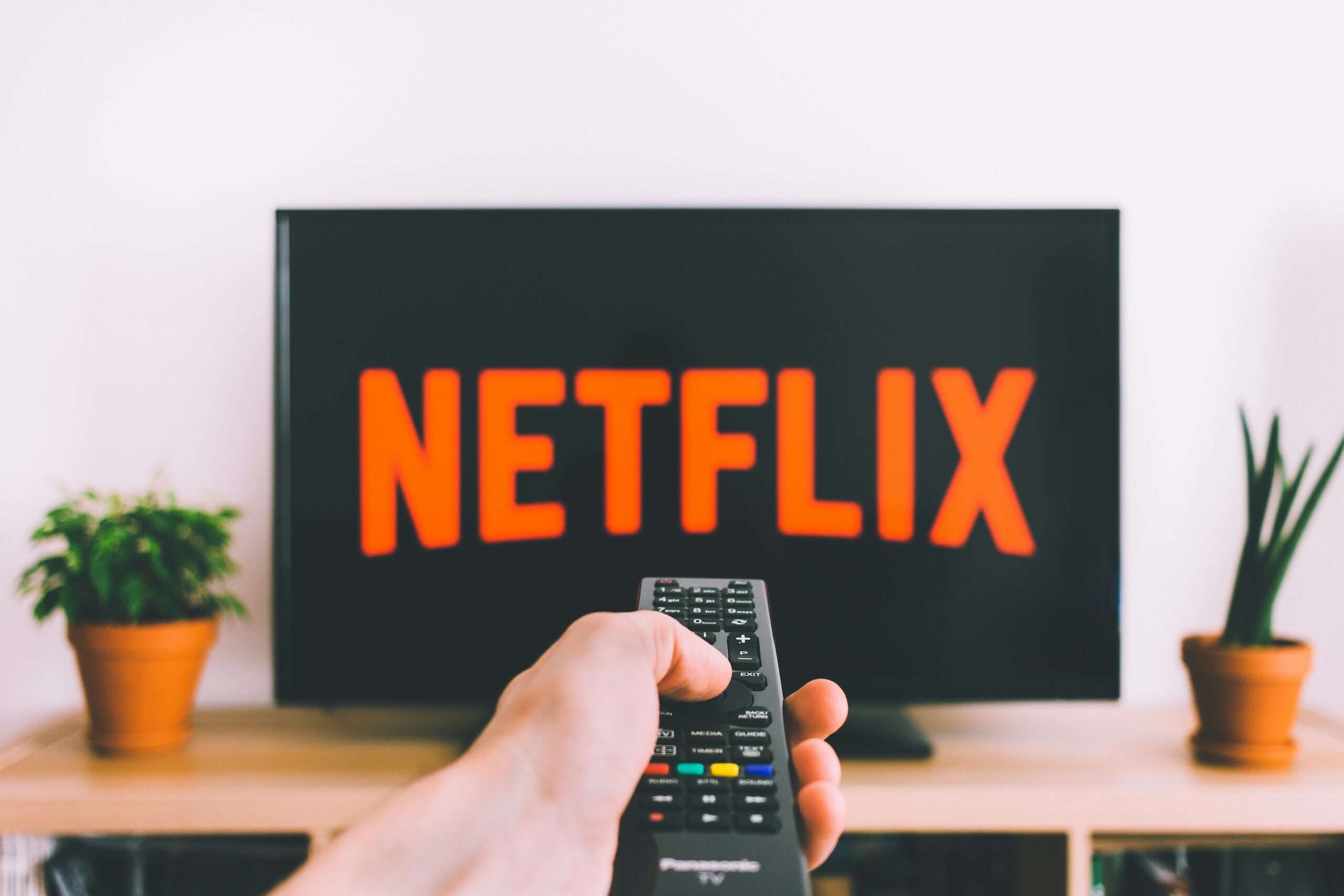 En TV med Netflix-logoen og en hånd med fjernkontrollen – illustrasjon til Netflix’ resultater for 2. kvartal 2026